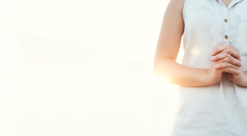 Photo of the torso of a woman standing with hands clasped to illustrate the article about 