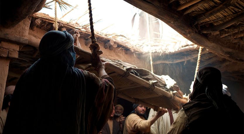 Photo illustration of a man being lowered through a roof to illustrate one of Jesus' healings, for the article What Can We Learn From Jesus’ Early Healings?